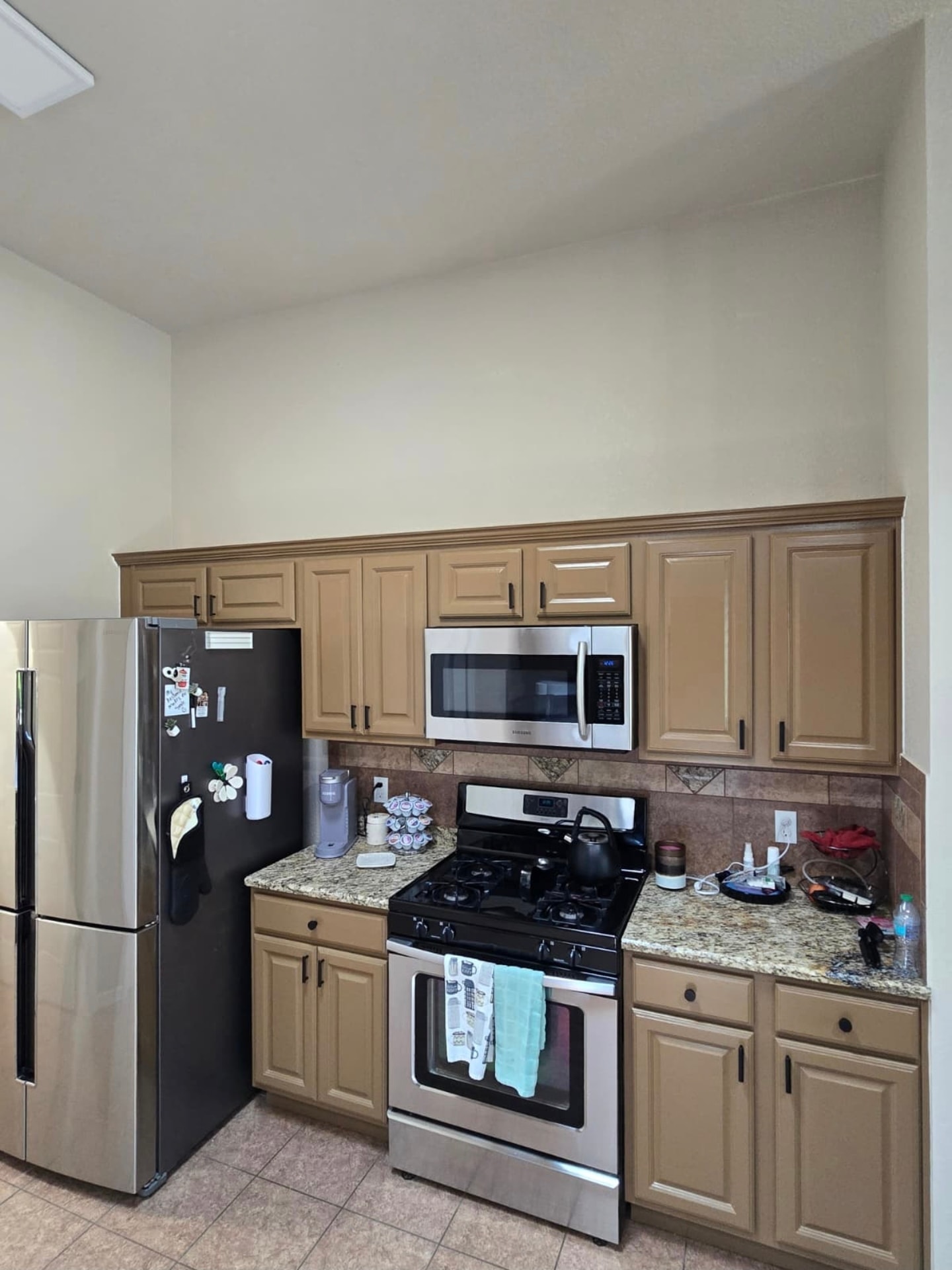 Kitchen with refinished tan cabinetry and stainless steel appliances