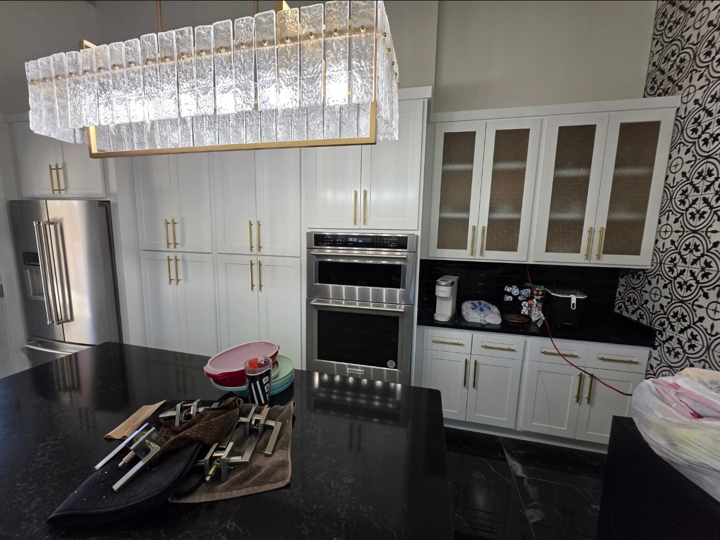White refinished kitchen cabinets with black countertops and decorative tile wall
