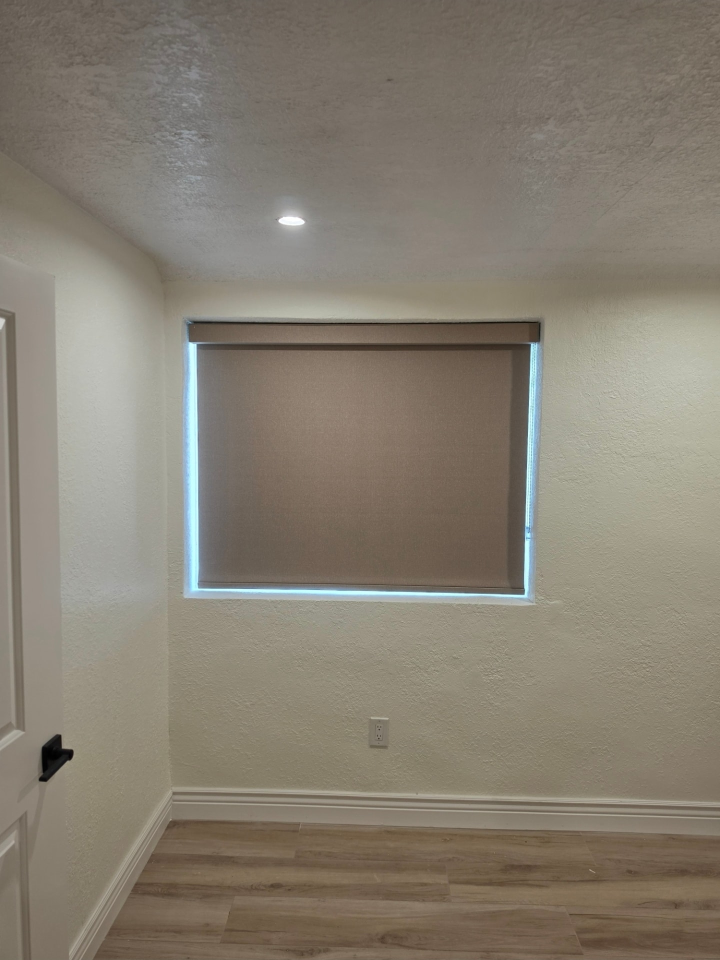 Taupe roller shade with LED-lit frame in a bedroom