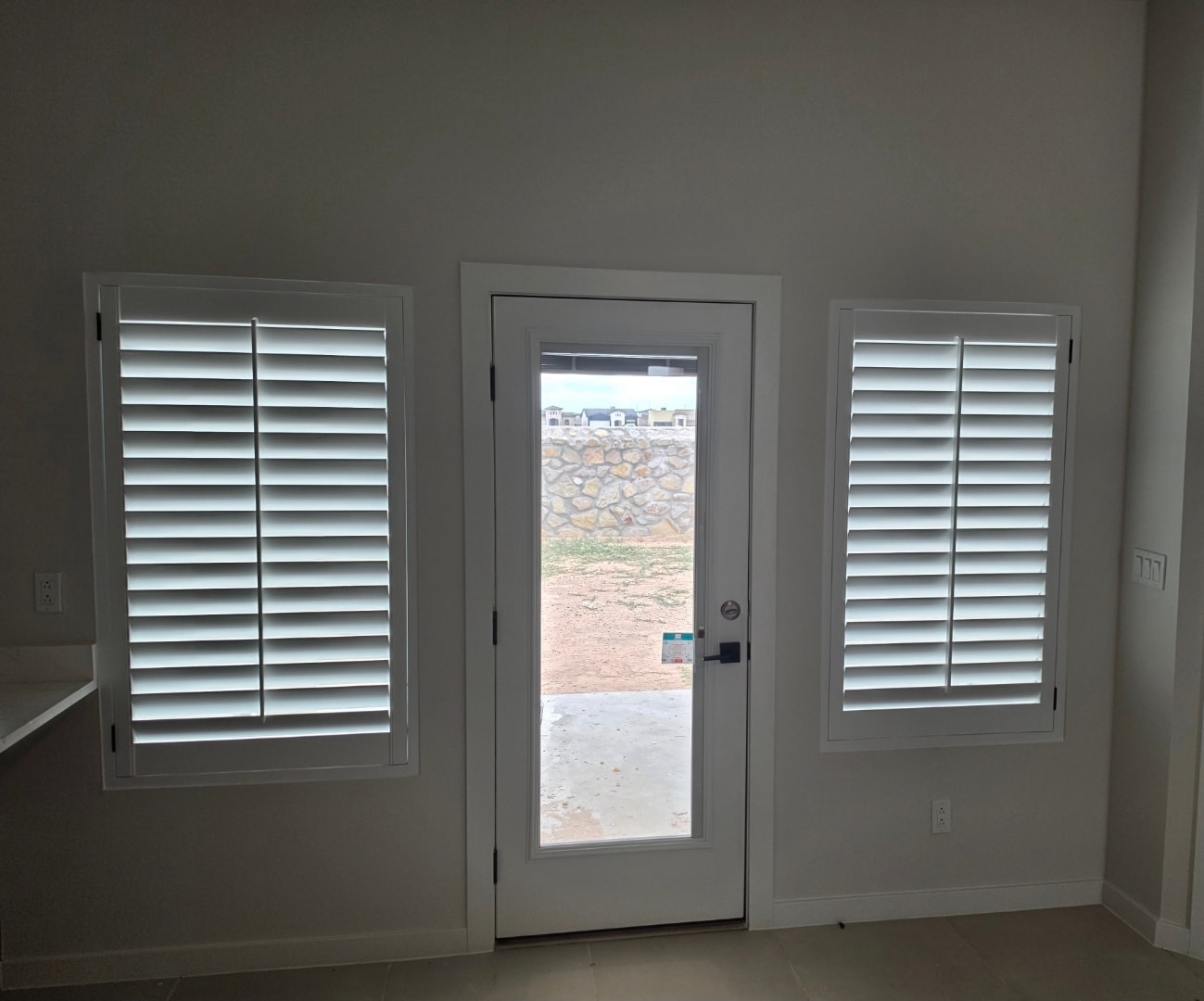 Plantation shutters flanking a glass door
