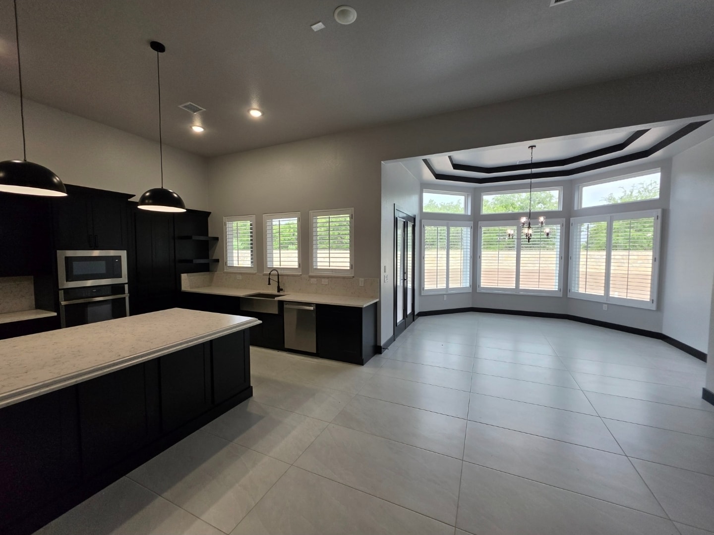 Plantation shutters in a modern kitchen and dining area with black cabinetry