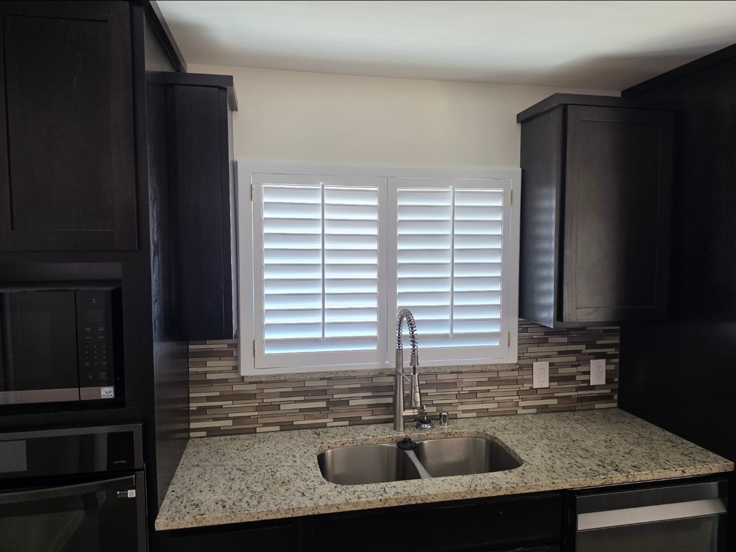 Plantation shutters above kitchen sink with tile backsplash